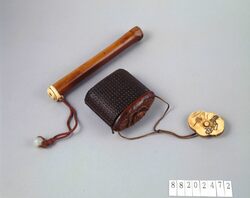 紙縒細工黒漆塗魚籠型蓋木製椿彫とんこつ提げたばこ入れ / Twisted Paper Work Tobacco Pouch with Camellia Carving with Fish Basket-shaped Lid Covered with Black Lacquer, with Netsuke and Pipe Case image