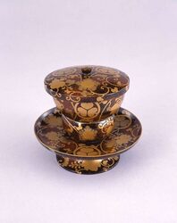 村梨子地葵葉菊紋散花桐唐草文蒔絵茶碗 / Nashiji-lacquered Hanakiri Karakusa Bowl with Aoihakikumon Crest image
