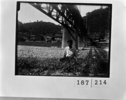 橋の下の河原に座る男性 / Man Sitting on the Riverside Beneath a Bridge image